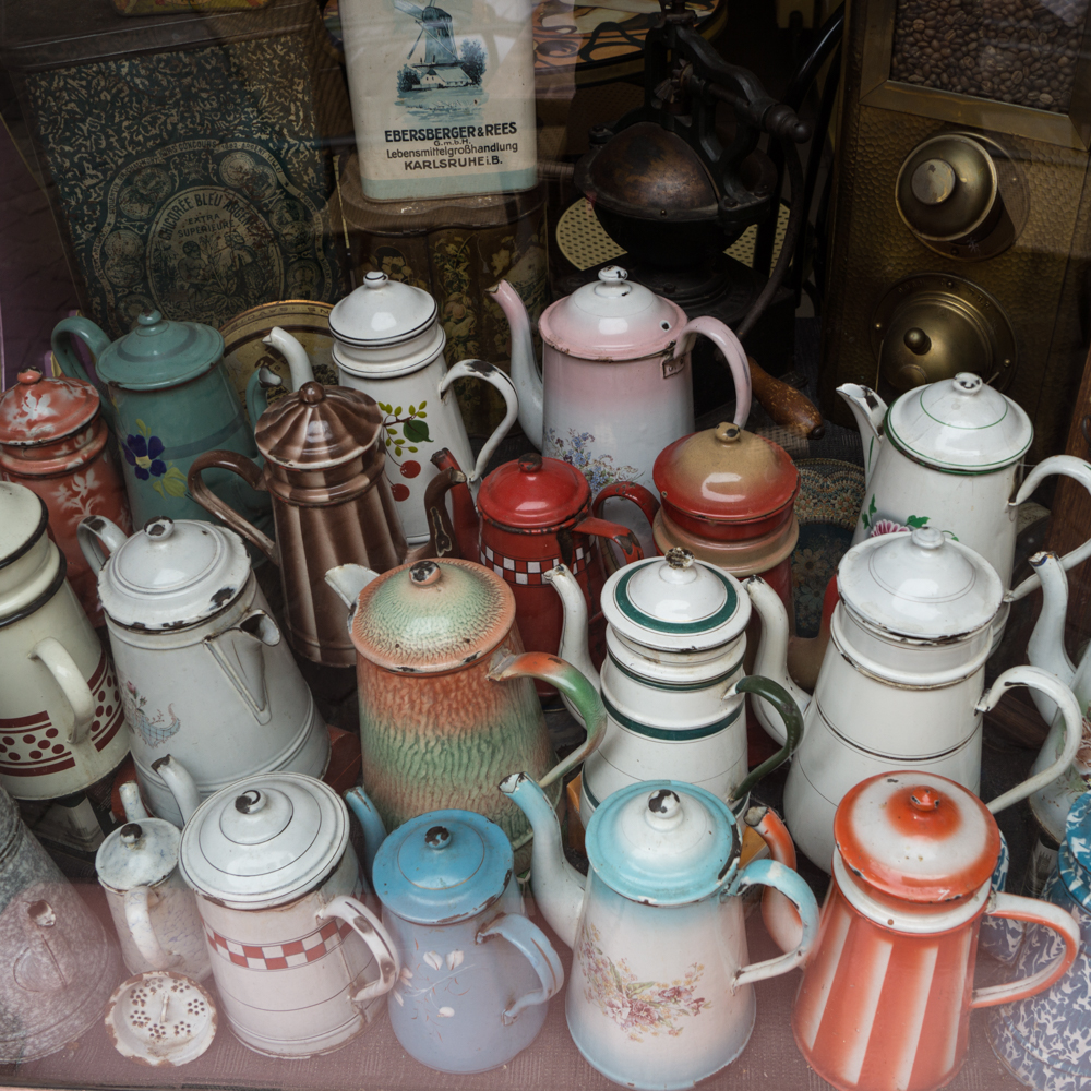 Schaufenster mit alten Kannen in einem Café in Colmar, Elsass. 