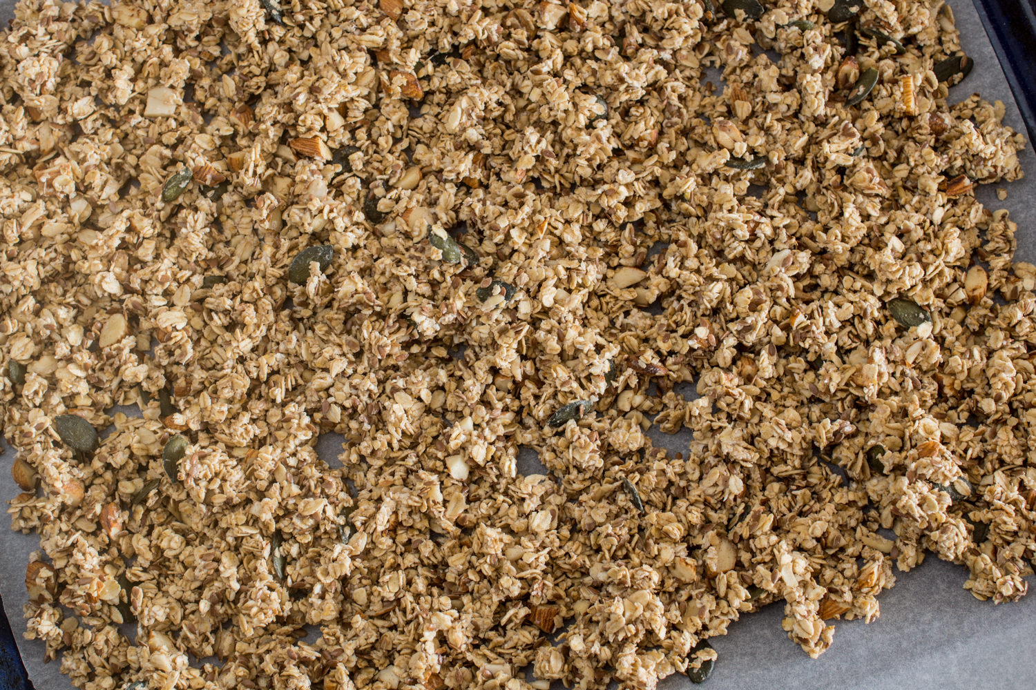 Granola auf ein Backpapier geben und im Backofen knusprig backen