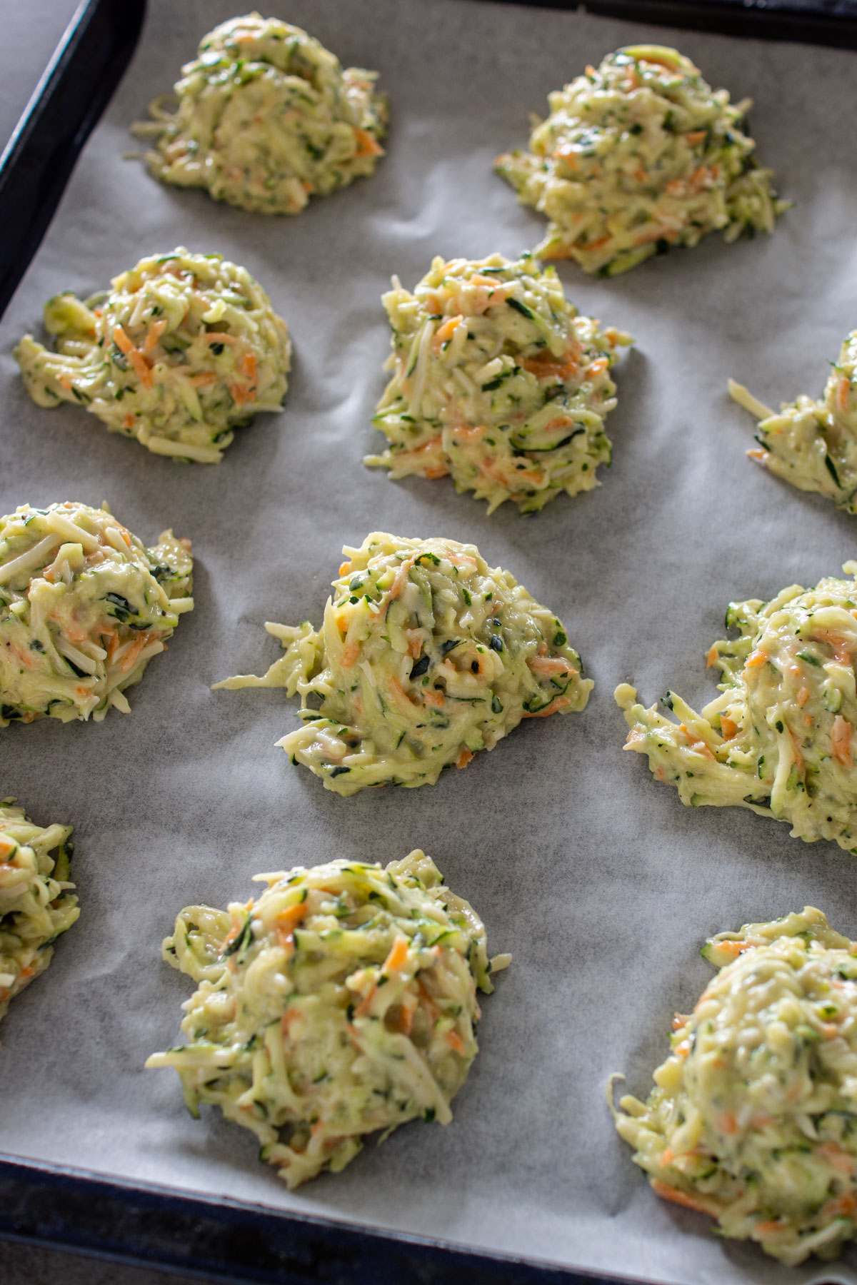 Zucchinipuffer auf dem Blech portionieren.