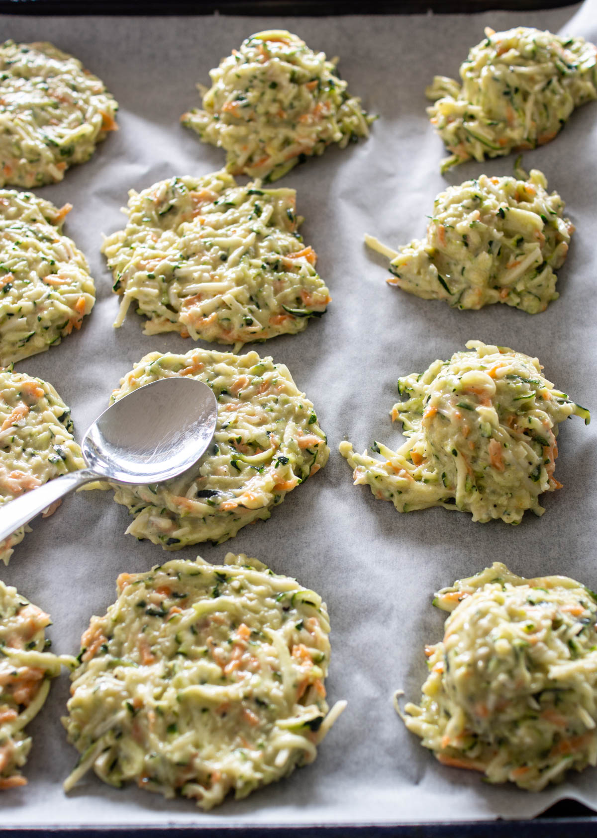 Die portionierte Zucchinimasse mit dem Löffel zu Puffern formen.